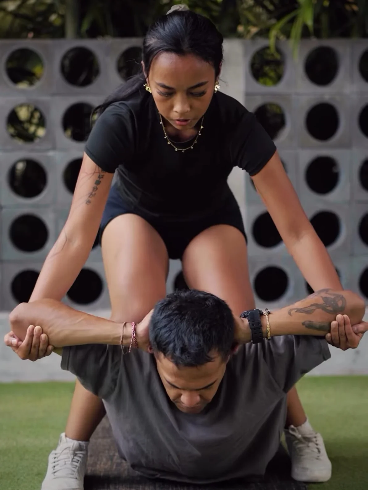 Ain guiding a client through a hands-on stretch outdoors.
